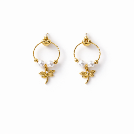 A pair of gold-plated earrings for women featuring a detailed dragonfly charm and three white pearls, shown on a white background.