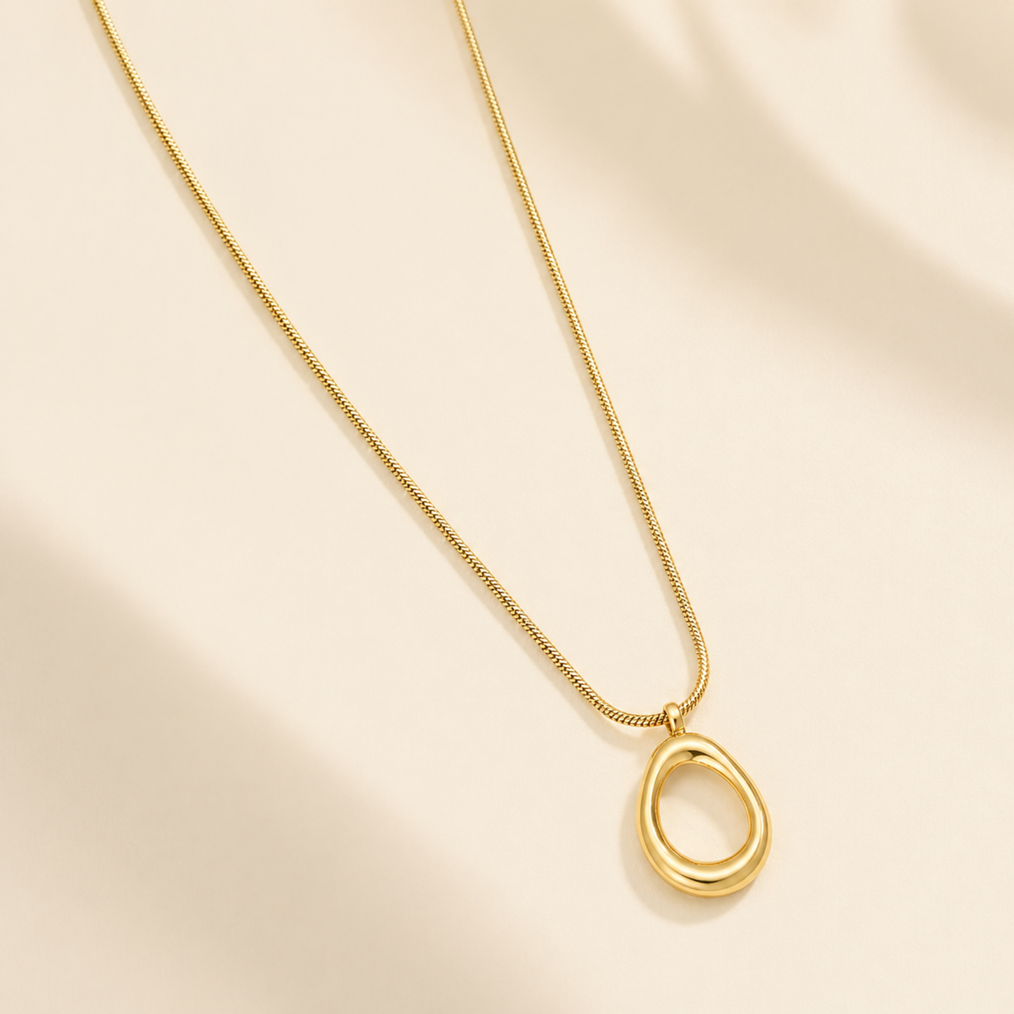 A close-view of a gold-plated stainless steel chain for women featuring a sleek snake link and a open-oval pendant