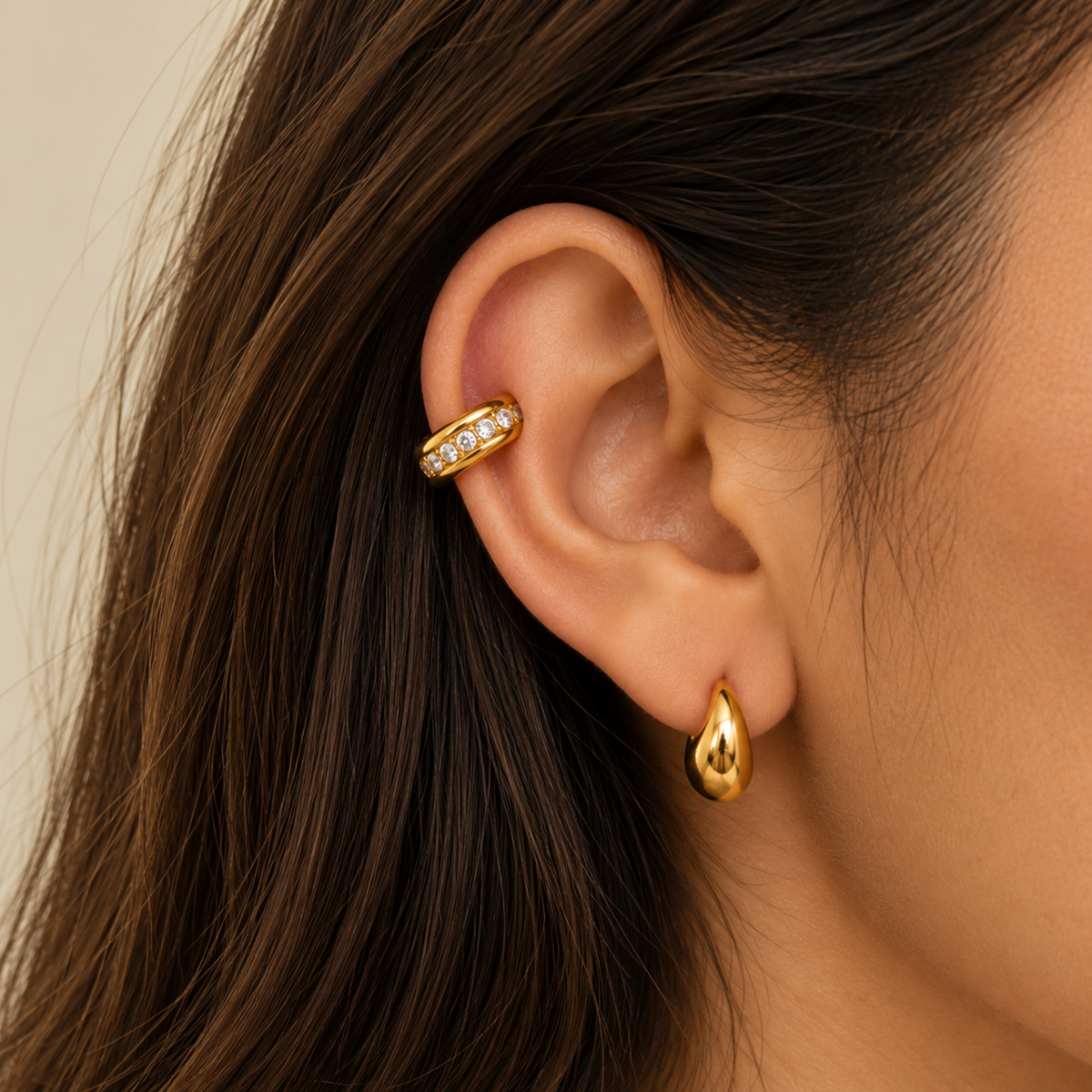 Gold-plated open ear cuff with a smooth rounded band and clear crystals set along the lower edge, on a model