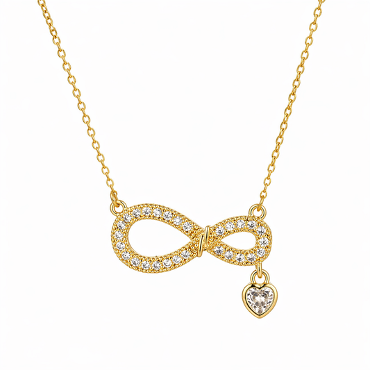 A close-view of a gold-plated stainless steel chain for women featuring an infinity symbol pendant set with sparkling crystals and a small dangling heart-shaped crystal charm.