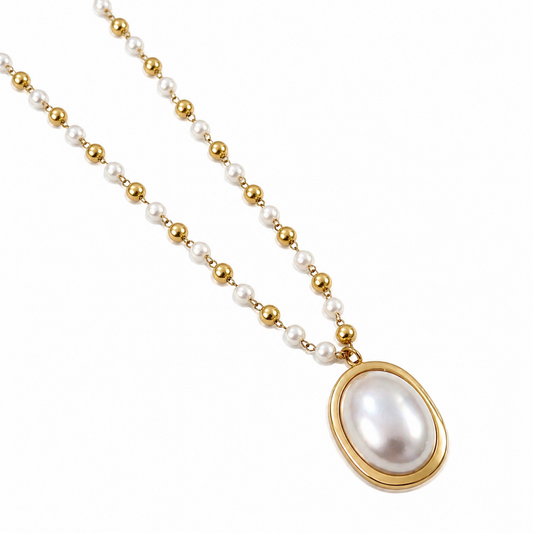 A close-view of a gold-plated stainless steel chain for women featuring alternating pearls and gold beads with a large oval pearl pendant.