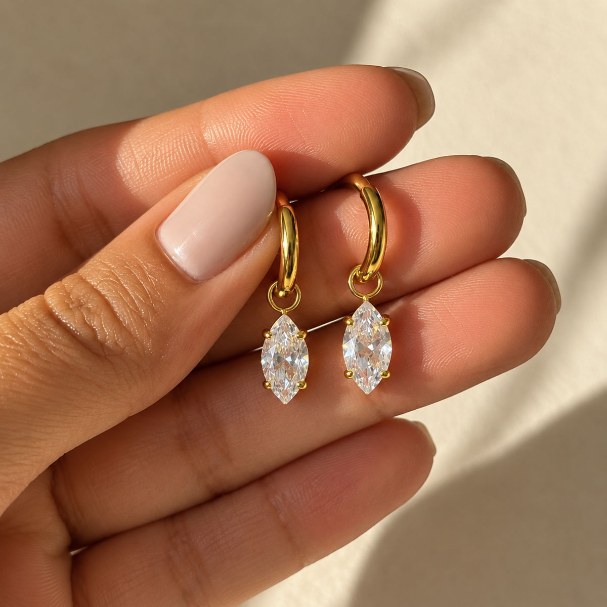 A close-view of crystal drop hoop earrings with marquise-cut clear crystals, available in gold