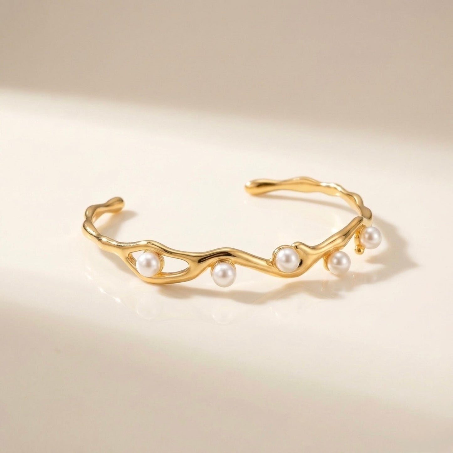A gold-plated wave cuff bangle for women featuring five set pearls