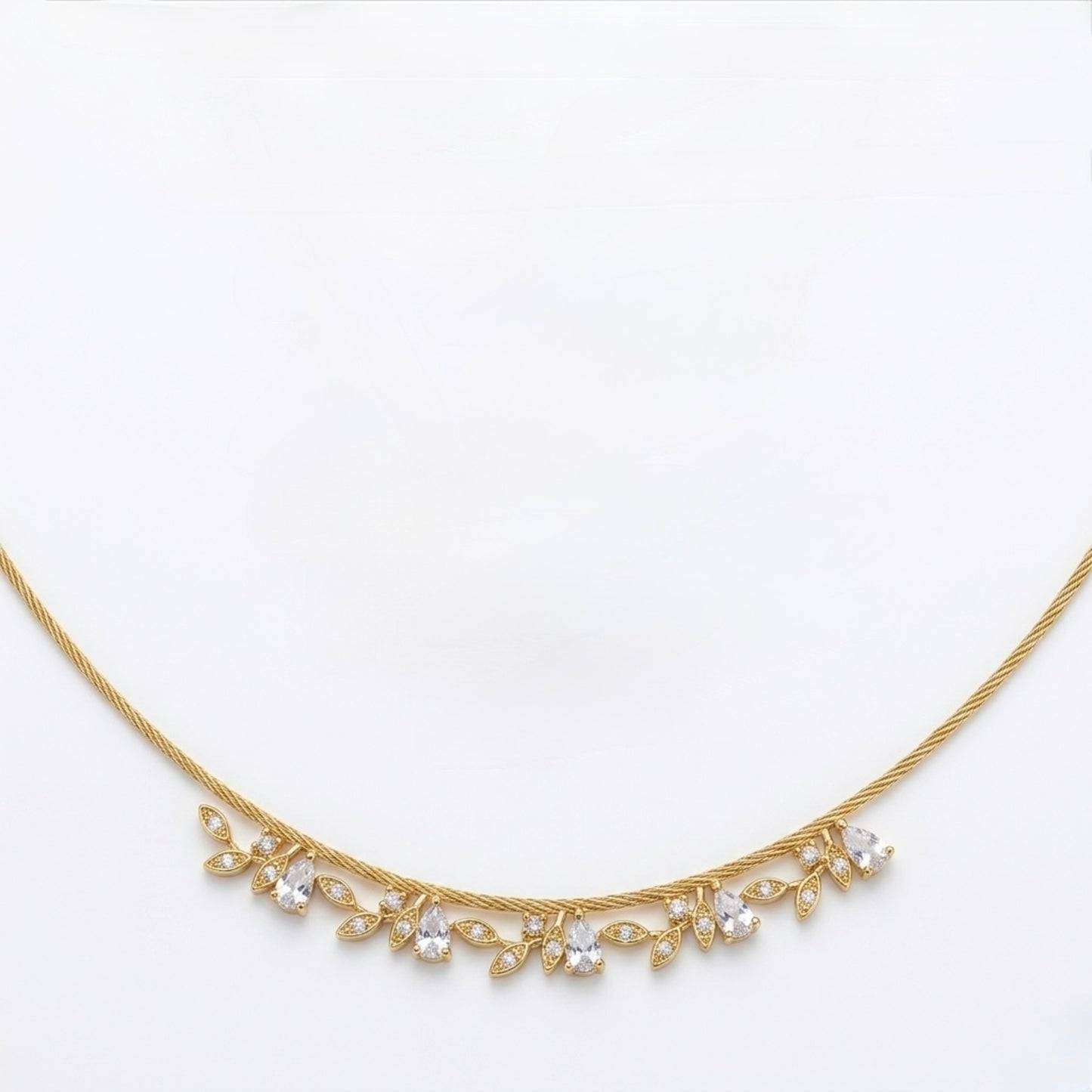 A close-view of a gold-plated stainless steel chain for women featuring a twisted cable design and a shimmering fringe of crystal leaf charms
