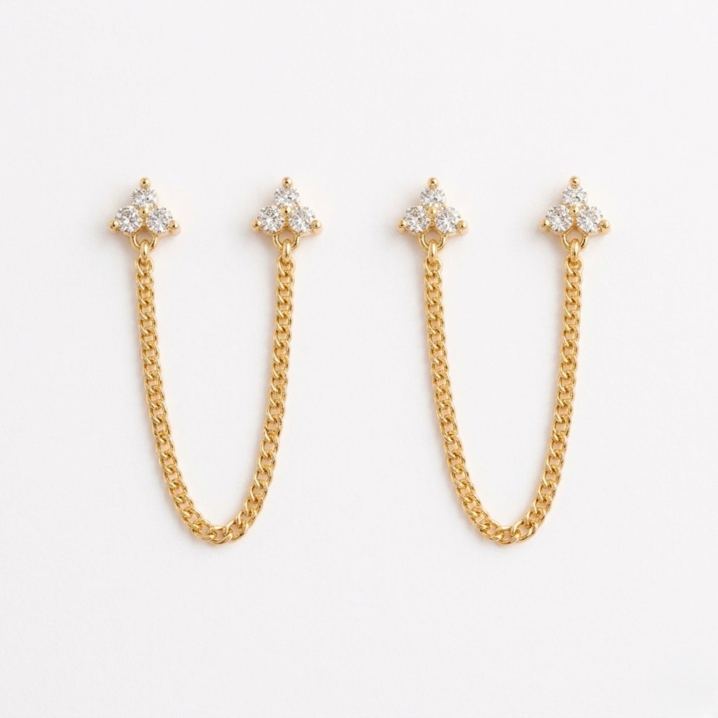 A pair of gold-plated ear chain earrings for women featuring two triple-stone white stone blossom studs connected by a shimmering gold chain on a white background