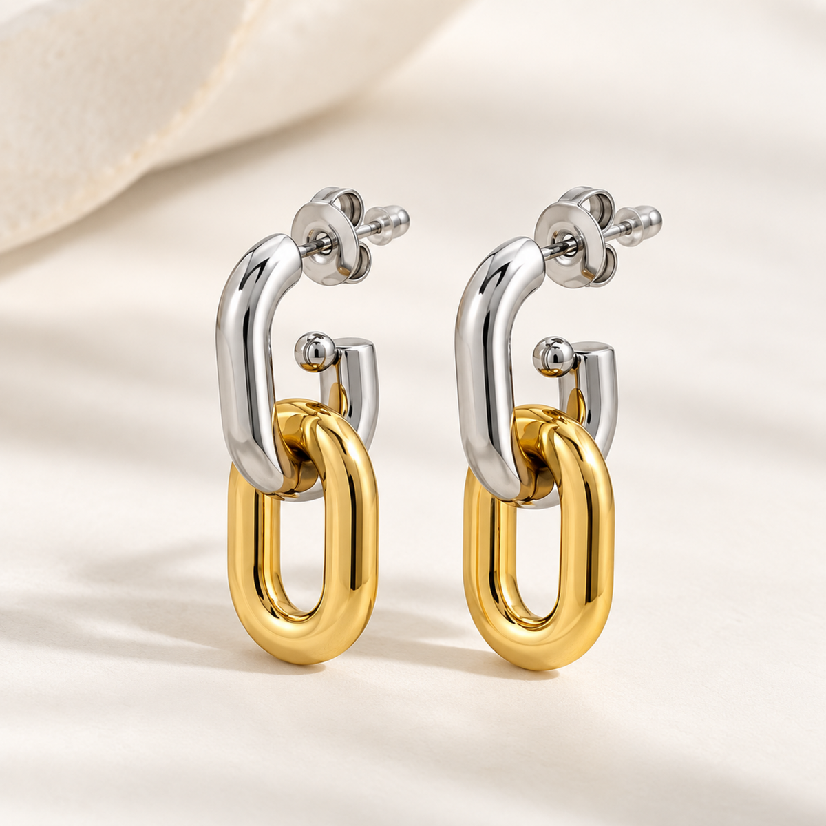 Two-tone gold and silver interlocking drop earrings for women with a sleek elongated loop design and polished finish on a neutral background