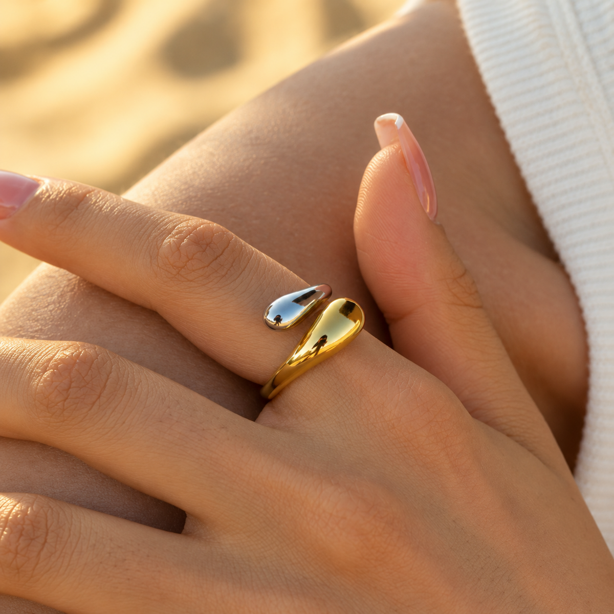 A close-view of a Two-Tone Sculptural Adjustable Ring with polished gold and silver curved elements in an open design.