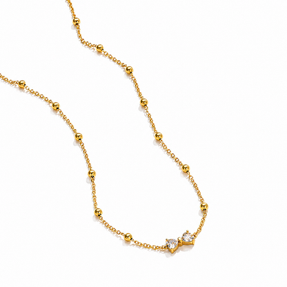 A gold-plated stainless steel chain for women featuring small gold beads and a central crystal bow charm