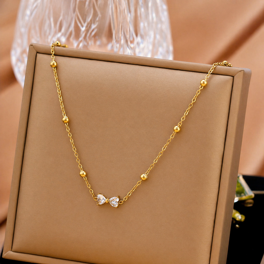 A gold-plated stainless steel chain for women featuring small gold beads and a central crystal bow charm