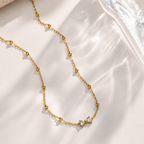 A gold-plated stainless steel chain for women featuring small gold beads and a central crystal bow charm