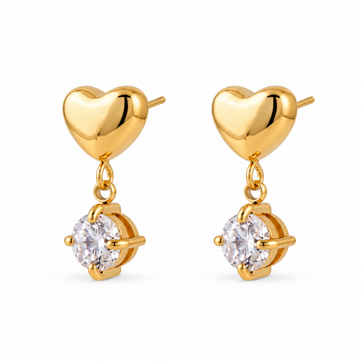 A pair of gold heart drop earrings with a polished gold heart and a clear round-cut gemstone in a prong setting, shown on a solid white background.