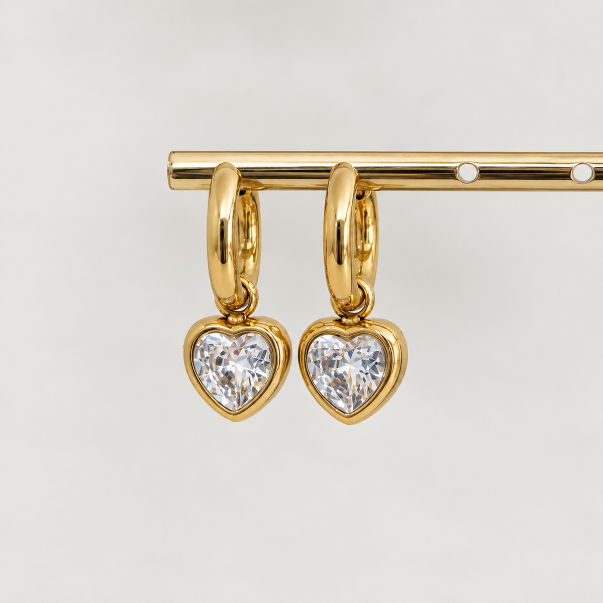Gold heart crystal hoop earrings for women with sparkling heart-shaped drops and PVD gold plated finish on display