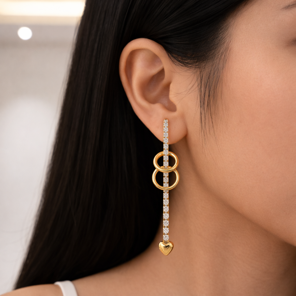 A gold-plated long earrings for women featuring a crystal bar, two interlocking gold rings, and a small heart charm at the base shown on a model