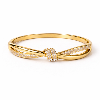A high-end gold-plated knot bangle for women featuring a sparkling white stones central knot and a double-band cross-over design on a white background