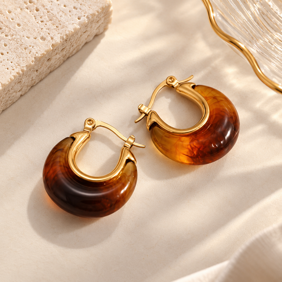 A close-view of a Amber resin hoop earrings for women with 18K gold plated accents, chunky rounded design and glossy finish