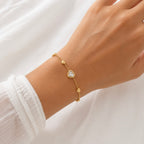 A gold-plated ladies bracelet featuring a central crystal heart and four small polished gold heart accents on a fine chain, shown on a model