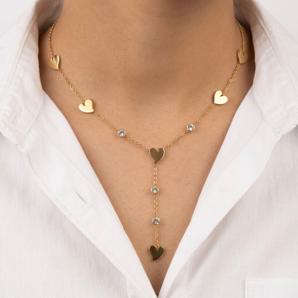 A gold-plated stainless steel Y-shaped chain necklace for women featuring minimalist heart charms and small round crystals, shown on a model