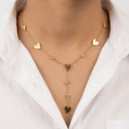 A gold-plated stainless steel Y-shaped chain necklace for women featuring minimalist heart charms and small round crystals, shown on a model