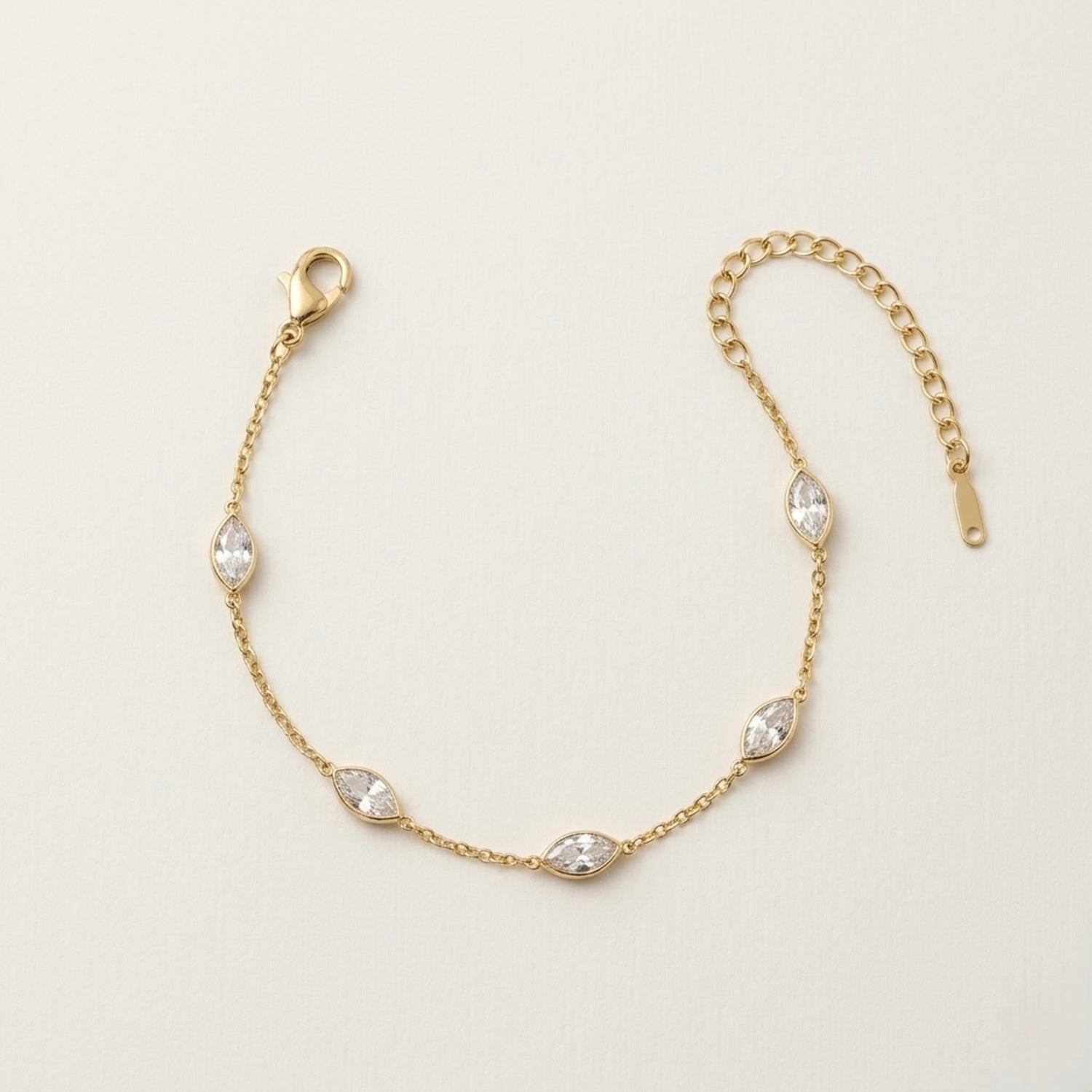 A dainty gold-plated chain bracelet for women featuring clear marquise-cut stone stations, shown on a clean off-white background