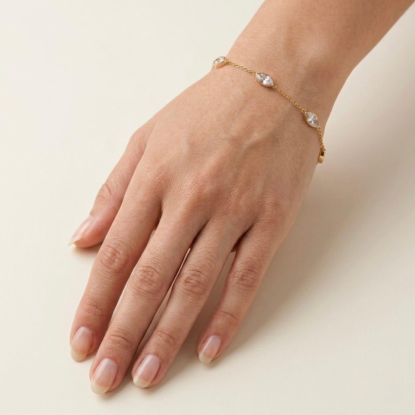 A dainty gold-plated chain bracelet for women featuring clear marquise-cut stone stations, shown on a model