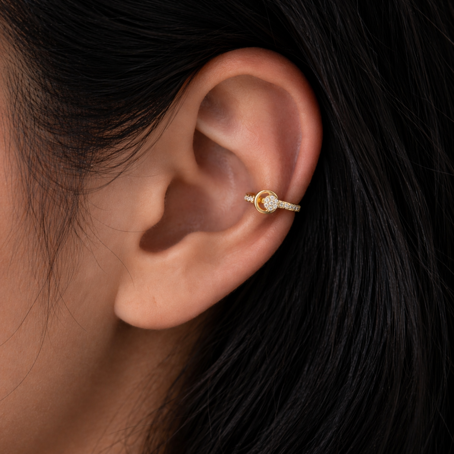 A gold-plated ear cuffs for women featuring five brilliant-cut stones, shown on a model ear