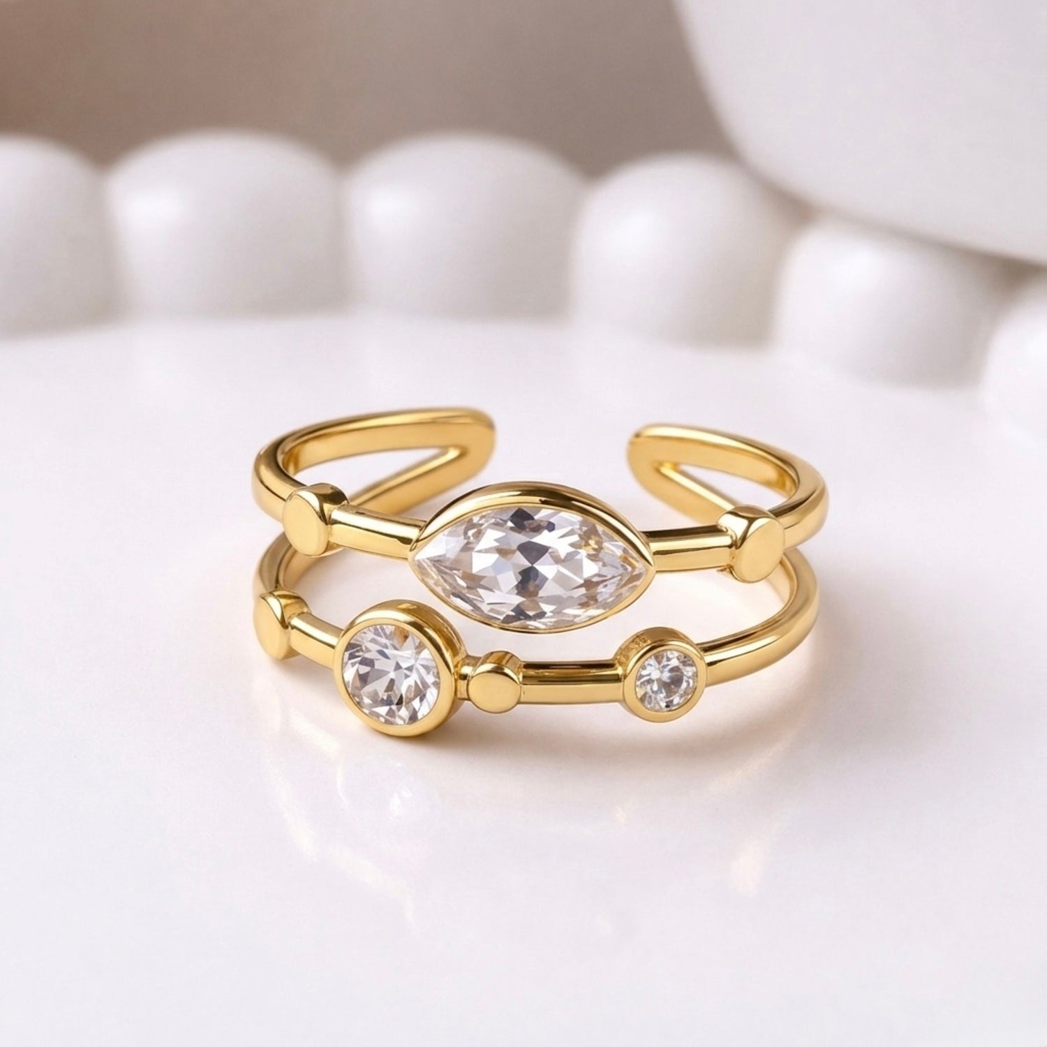 A gold plated adjustable ring for women with a double-band design featuring a central marquise-cut white stone on a white background