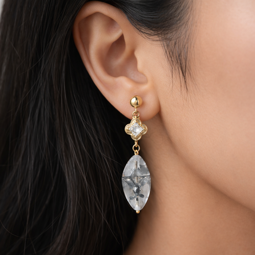 A gold-plated long earrings for women featuring a princess-cut stone in a mandala setting and a large marquise-cut clear drop stone on a model