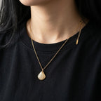 A close-view of a gold-plated stainless steel chain for women featuring a ribbed seashell pendant with four small crystals