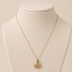 A gold-plated stainless steel chain for women featuring a ribbed seashell pendant with four small crystals on jewellery display