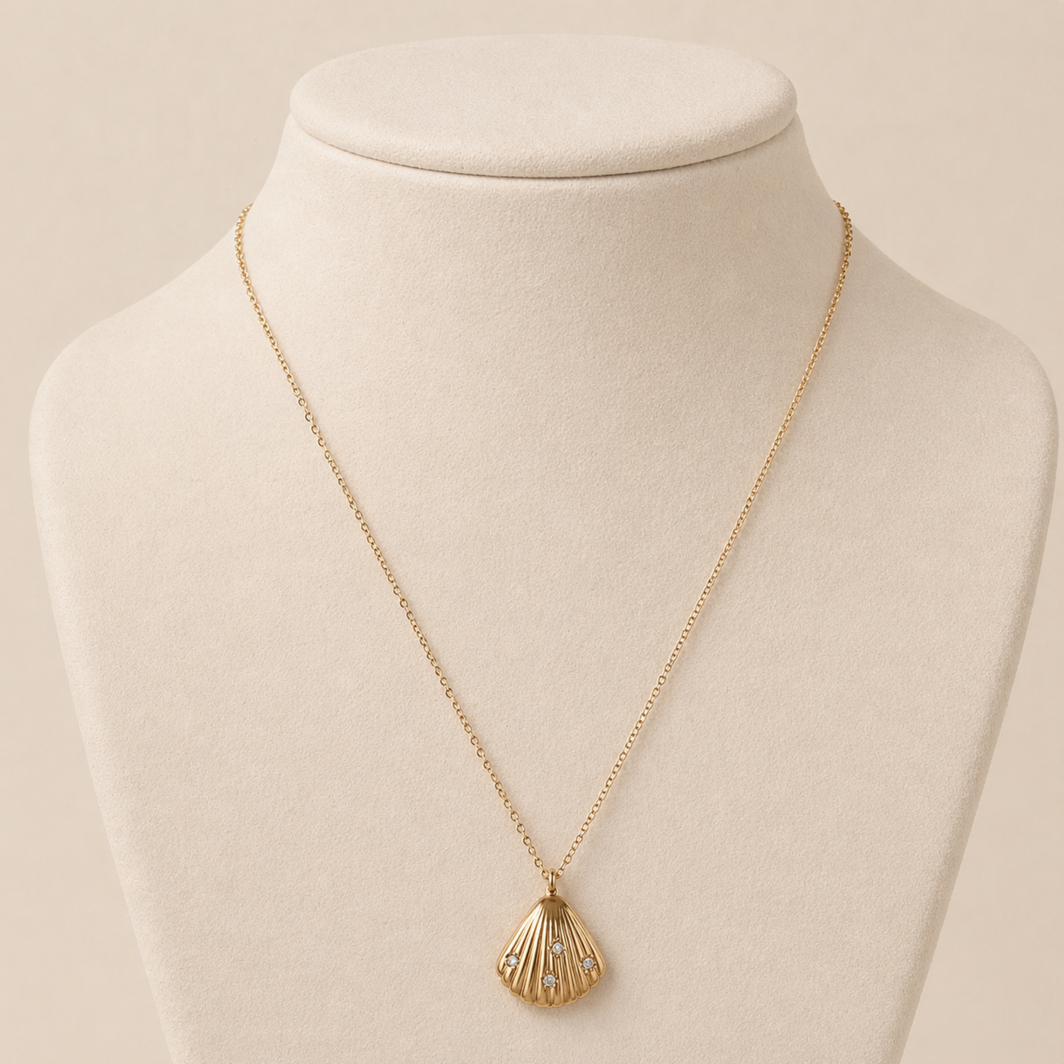 A gold-plated stainless steel chain for women featuring a ribbed seashell pendant with four small crystals on jewellery display