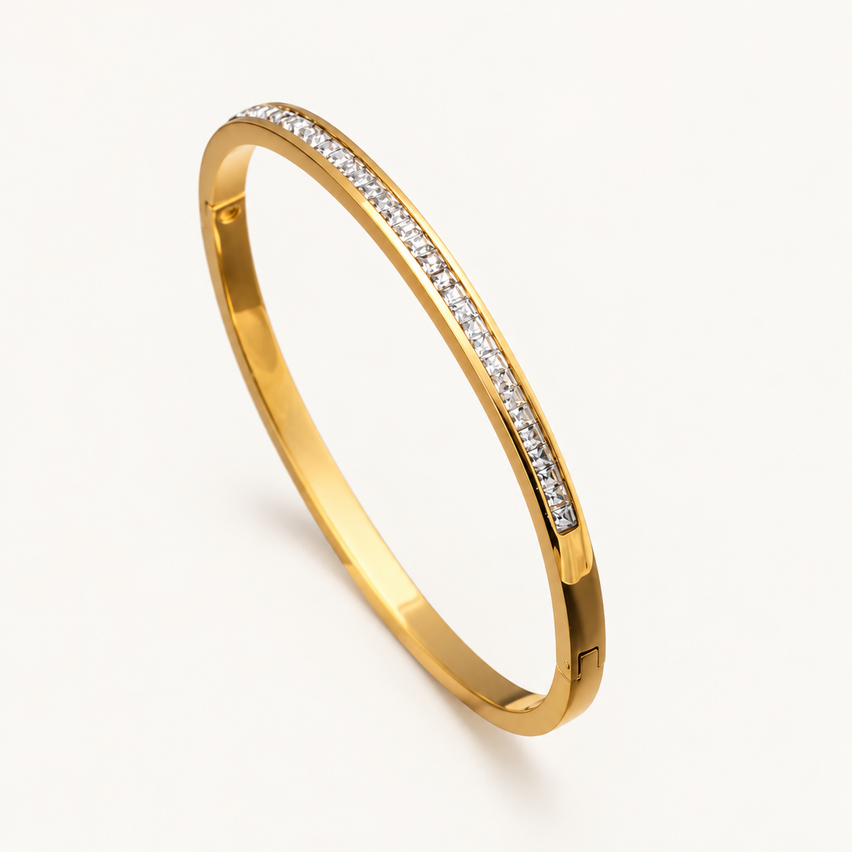 A close-view of a Crystal Bangle Bracelet with clear square-cut crystals set along a polished gold-plated band.