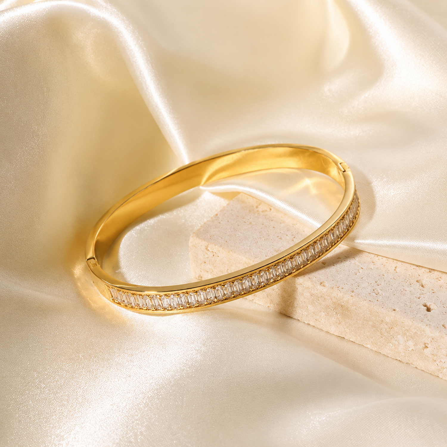 A gold-plated hinged bangle for women featuring a continuous row of channel-set baguette crystals with a secure side-clasp