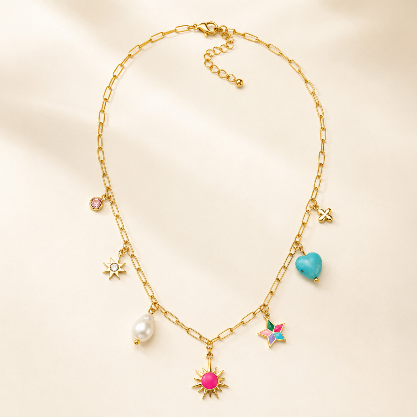 A gold-plated stainless steel chain for women featuring paperclip links and seven colorful charms including a pearl, heart, and sun