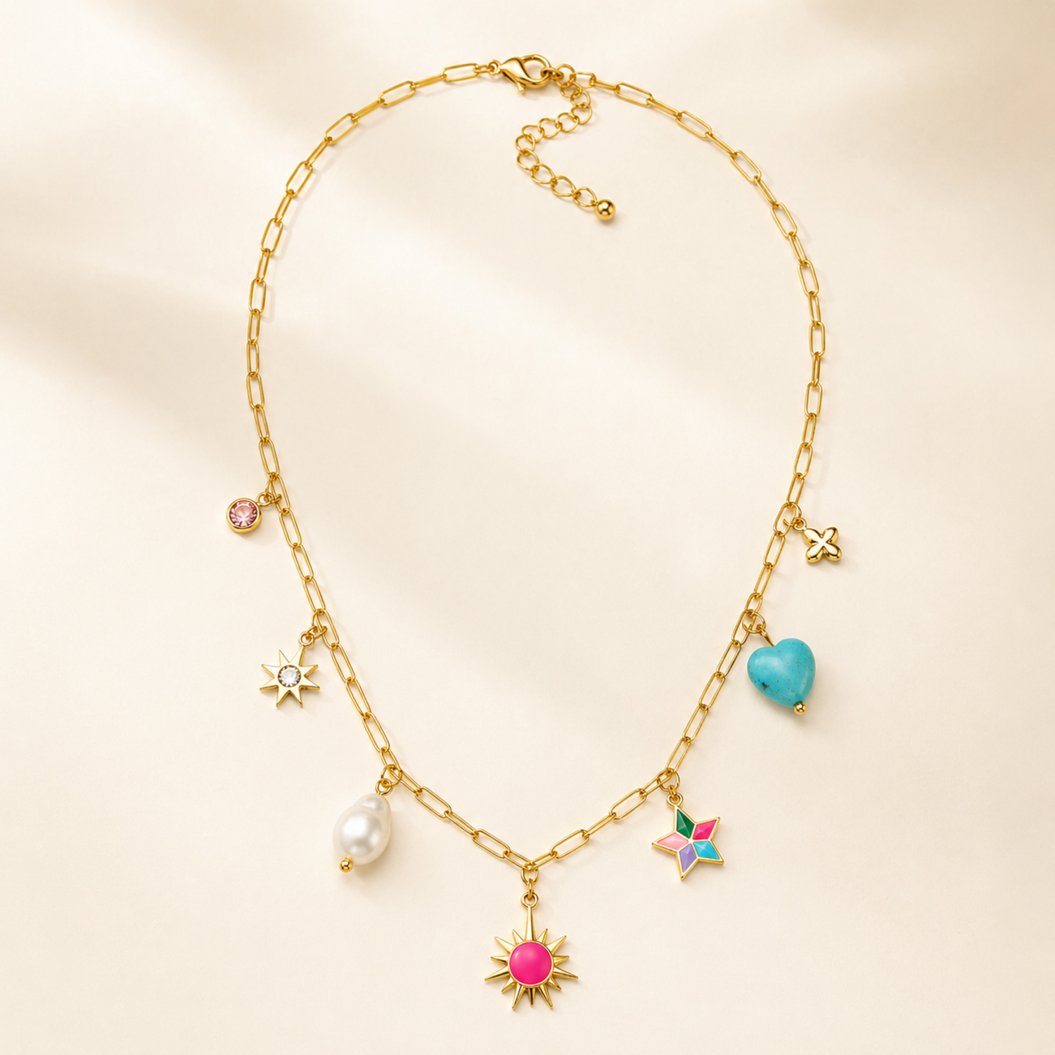 A gold-plated stainless steel chain for women featuring paperclip links and seven colorful charms including a pearl, heart, and sun