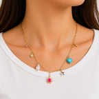 A gold-plated stainless steel chain for women featuring paperclip links and seven colorful charms including a pearl, heart, and sun, shown on a model