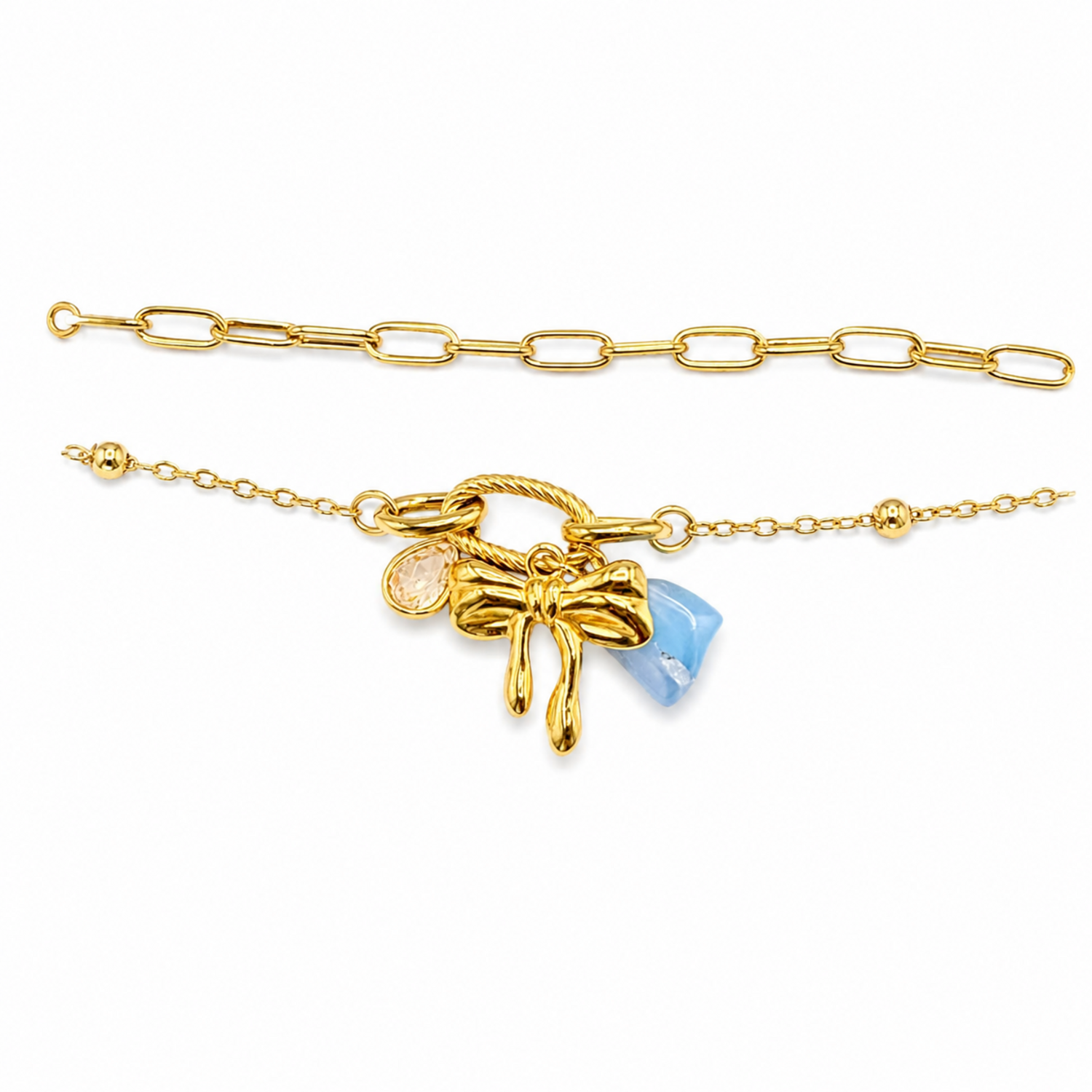 A close-view of a gold-plated layered chain bracelet for women featuring a paperclip chain, a satellite chain, a gold bow charm, and a blue stone
