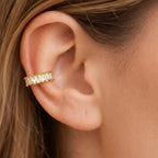 A gold-plated ear cuff for women featuring brilliant prong-set baguette-cut white stones, shown on a model ear