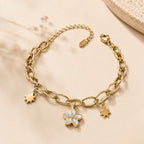 A gold-plated chain bracelet for women featuring a central mother-of-pearl flower charm and two polished star charms on a thick oval-link chain.