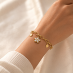A gold-plated chain bracelet for women featuring a central mother-of-pearl flower charm and two polished star charms on a thick oval-link chain, shown on a model