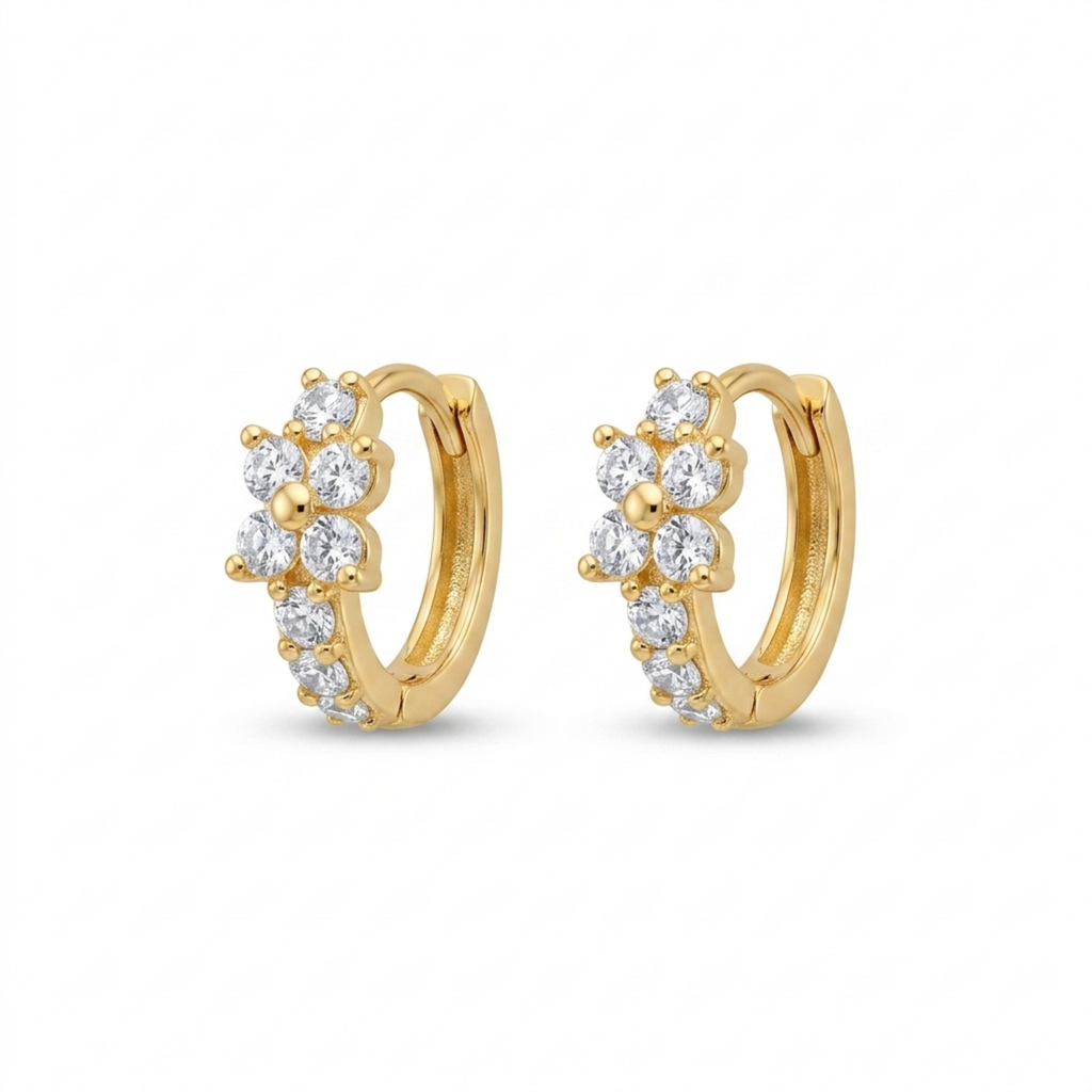 A pair of gold-plated huggie hoop earrings for women featuring a small clear crystal flower design, on a white background