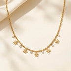 A gold-plated stainless steel chain for women featuring a woven texture with dangling gold flowers and round crystal charms