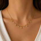 A gold-plated stainless steel chain for women featuring a woven texture with dangling gold flowers and round crystal charms, shown on a model