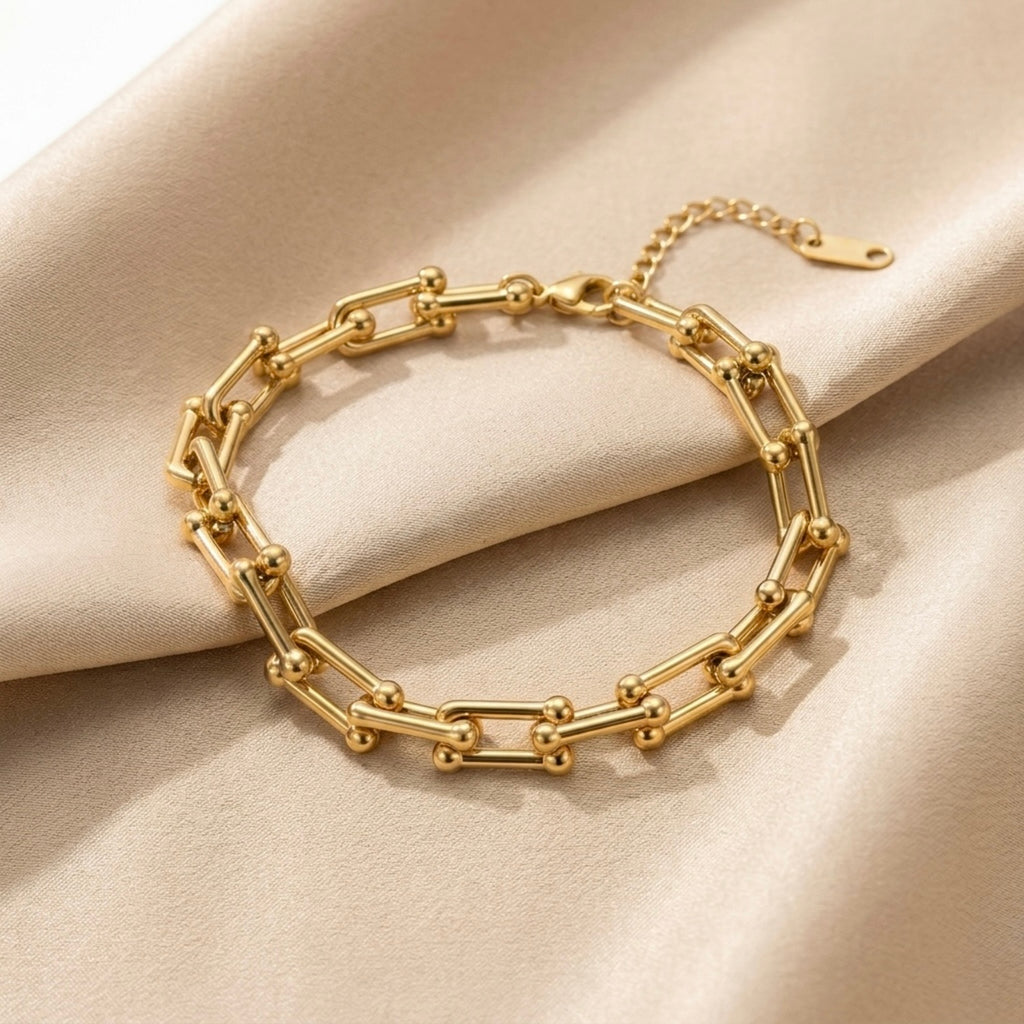 Gold chain bracelet on a beige fabric background