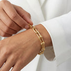 Gold bracelet on a wrist with a white background