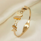 A gold-plated cuff bangle for women featuring three frosted-finish butterfly charms and polished circular links.