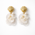 Pair of earrings with gold shell-like tops and pearl-like droplets on a white background