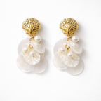 Pair of earrings with gold shell-like tops and pearl-like droplets on a white background