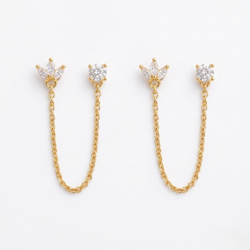A pair of gold-plated ear chain earrings for women featuring a marquise-cut floral stud and a round white stone stud connected by a delicate gold chain on a white background