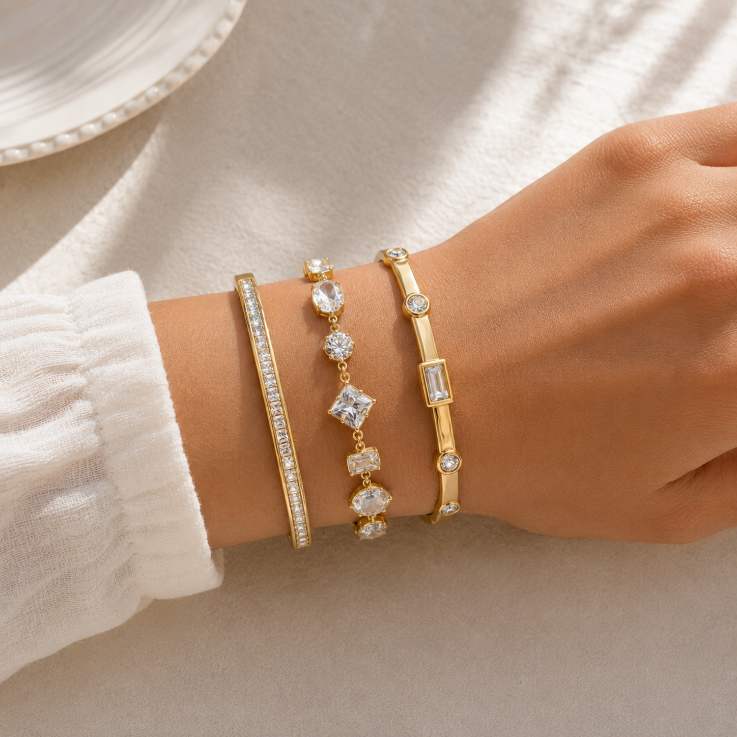 A three-piece gold-plated bracelet stack for women featuring an iced eternity bangle, a multi-cut geometric crystal chain bracelet, and a polished bezel-set crystal bangle on a model