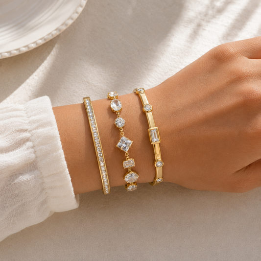 A three-piece gold-plated bracelet stack for women featuring an iced eternity bangle, a multi-cut geometric crystal chain bracelet, and a polished bezel-set crystal bangle on a model